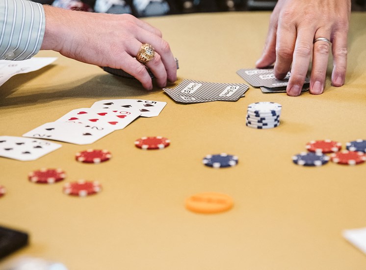hands playing with cards and poker chips on a table